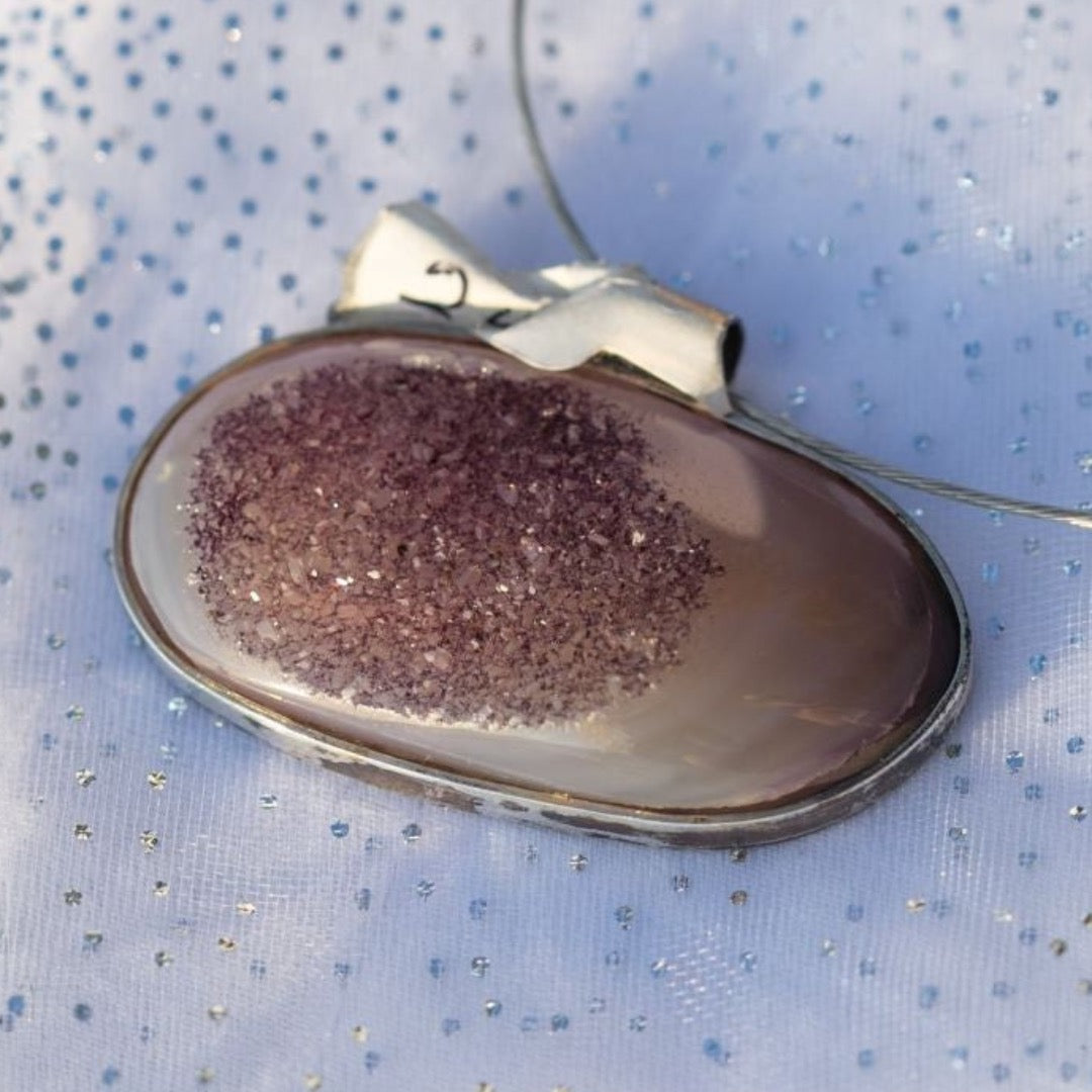 Joya de amatista que deja ver sus millares de puntos brillantes, este accesorio no puede faltar en el joyero de la mujer líder. Da calma, estrategia, precisión, buenas acciones y le ayuda a tomar mejores decisiones a quien la usa. Esta hermosa amatista le ayudara a tener claridad a dónde quiere ir, mejorará su conexión con el chakra de la garganta para que su comunicación sea asertiva y fluida.